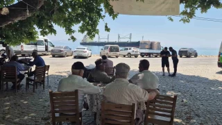 Karaya oturan gemiyi ky kahvesinden izliyorlar