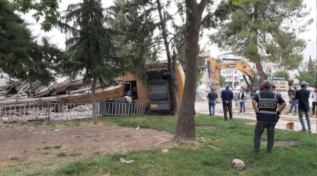 Hasarlı bina yıkımı esnasında iş makinesi devrildi